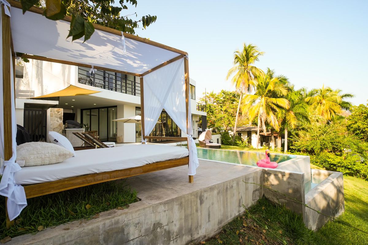 Poolside canopy daybed among palm trees